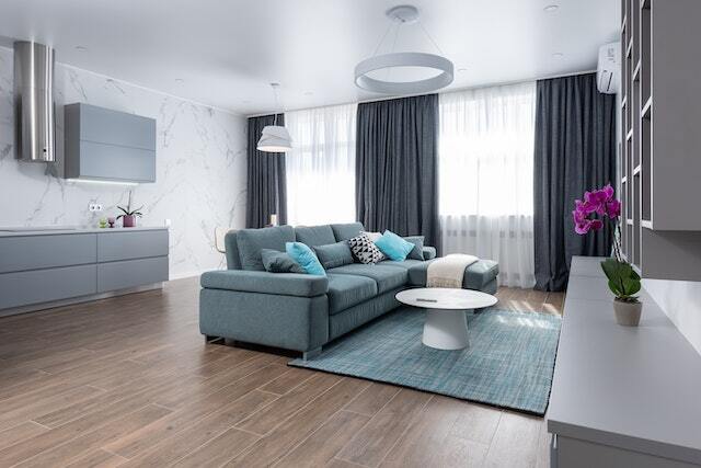 living room with dark wood floors and blueish grey couch rug and furniture